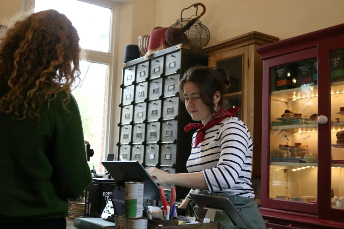 A cashier serves a customer at a shop counter.
